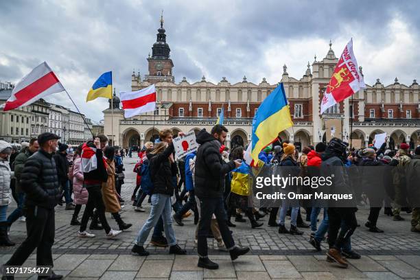 Ukrainians hold banners and Ukrainian national flags during a protest for peace in Ukraine at Krakow's UNESCO listed Main Square on February 20, 2022...