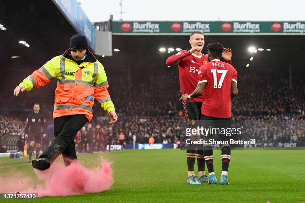 Fred of Manchester United celebrates with teammate Scott McTominay after scoring their side's third goal as a steward kicks a flare off of the pitch...