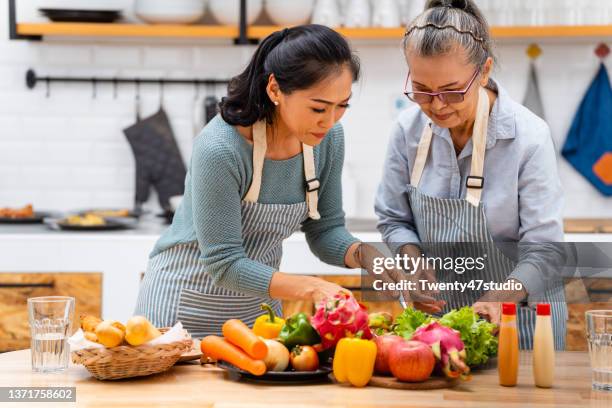 happy family enjoys cooking healthy food in the kitchen - asian mom cooking stock pictures, royalty-free photos & images