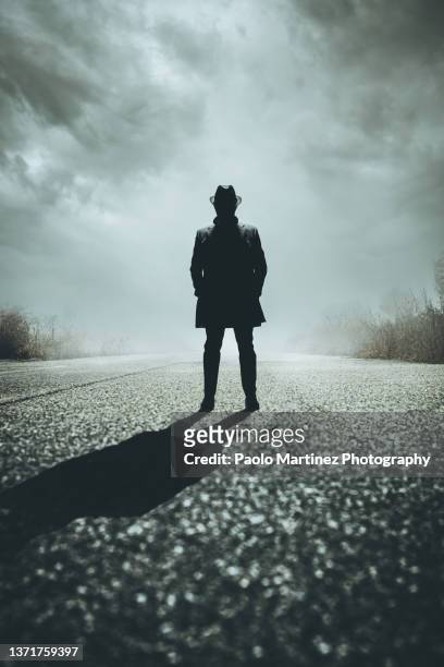 front view of silhouette gangster standing on road - gângster - fotografias e filmes do acervo