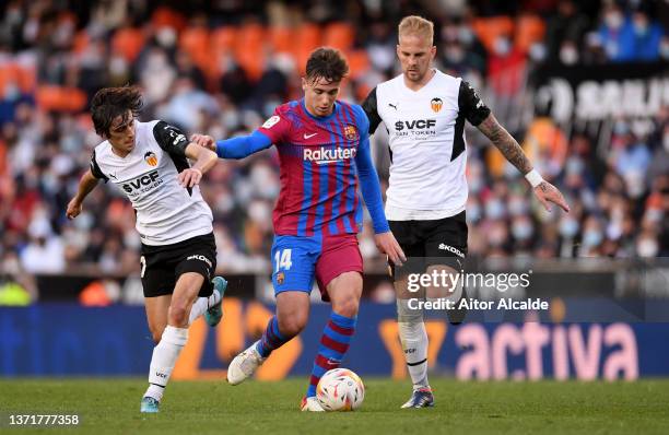 Nico Gonzalez of FC Barcelona is challenged by Bryan Gil and Hugo Guillamon of Valencia CF during the LaLiga Santander match between Valencia CF and...