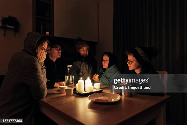 família sentada perto das velas durante o apagão. - vela equipamento de iluminação - fotografias e filmes do acervo