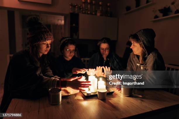 familia sentada junto a las velas durante el apagón. - cold temperature fotografías e imágenes de stock