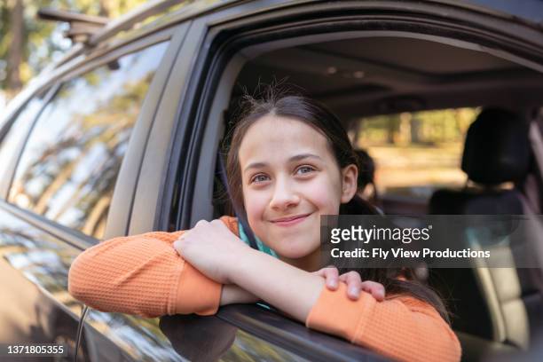 glückliches teenager-mädchen, das im auto fährt - girl side view stock-fotos und bilder