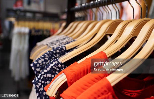 close-up view of women's dresses hanging on clothes hooks in mall store rack, latest seasonal collection. - damkl�äder bildbanksfoton och bilder