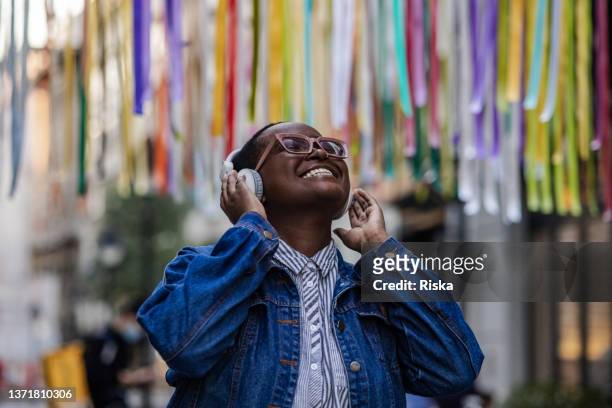 giovane donna con cuffie wireless che ascolta musica all'aperto - genere musicale foto e immagini stock