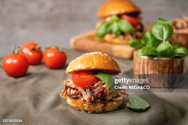Set of homemade mini burgers with stew beef, tomatoes and basil standing on kitchen table with ingredients around, Modern delicious fast food.