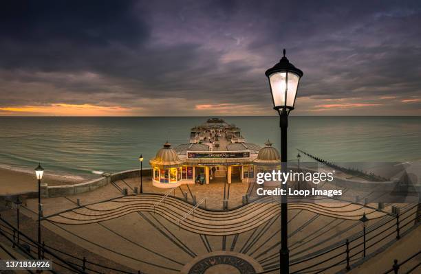 The street lights start to come on as the sun sets at Cromer pier.