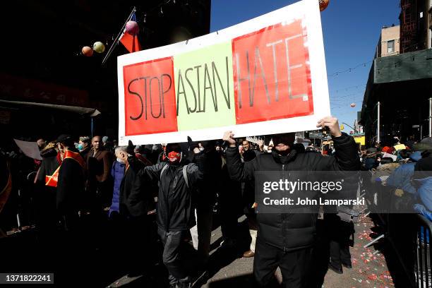 Participants hold a "Stop Asian Hate" sign as they march in the Chinatown Lunar New Year Parade on February 20, 2022 in New York City.