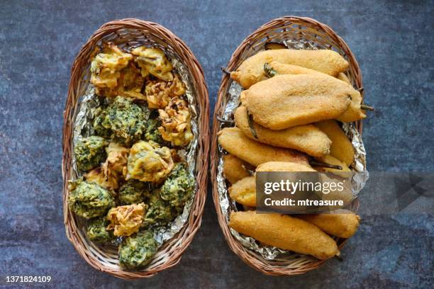 imagem de cestos de vime forrado com papel alumínio, fritters de chilli verde caseiro (mirch pakora), bhajis de cebola crocante e palak pakora (fritos de espinafre), lanche vegetariano da culinária indiana, fundo cinza, vista elevada - tin foil costume - fotografias e filmes do acervo