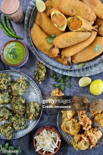 image of tray with patterned plate of homemade green chilli fritters (mirch pakora), plate crispy onion bhajis and palak pakora (spinach fritters), glass chai bowl mint and coriander chutney, indian cuisine vegetarian snack, grey background, elevated view - chai tea stock pictures, royalty-free photos & images