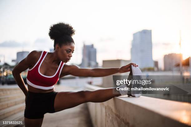 stretching her legs after a tough running day - woman stretching sunset stockfoto's en -beelden