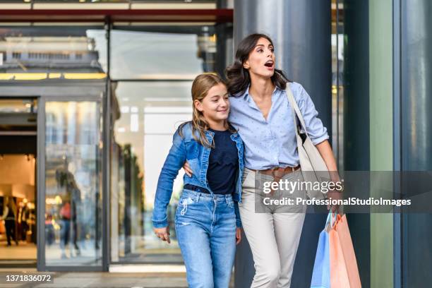 ritratto di madre e figlia in piedi vicino alla vetrina e navigando nel negozio. - mum daughter foto e immagini stock