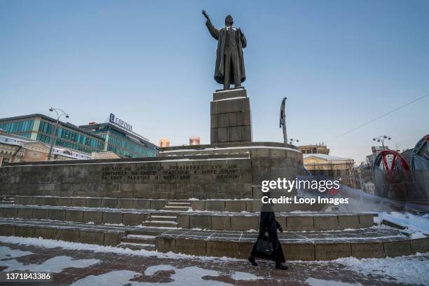 Russian woman passes underneath a statue of Lenin in Yekaterinburg in Russia.