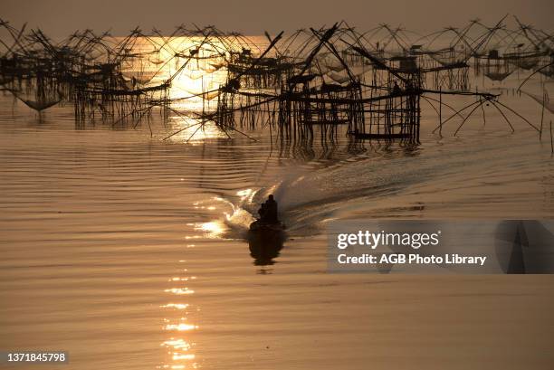 Thailand, Phatthalung, Shore-operated lift net, Fisherman on boat, Sunrise.