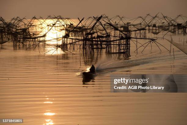 Thailand, Phatthalung, Shore-operated lift net, Fishermen on boat, Sunrise.