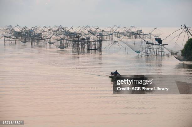 Thailand, Phatthalung, Shore-operated lift net, Fishermen on boat, Sunrise.