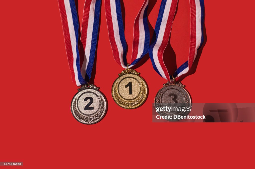 Gold, silver and bronze sports achievement medals for first, second and third place, on a red background. Concept of winner, medals, honor and sports competition.