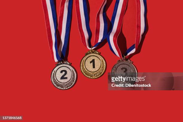 gold, silver and bronze sports achievement medals for first, second and third place, on a red background. concept of winner, medals, honor and sports competition. - 第三名 個照片及圖片檔