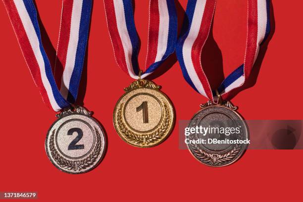 gold, silver and bronze sports achievement medals for first, second and third place, on a red background. concept of winner, medals, honor and sports competition. - third place fotografías e imágenes de stock