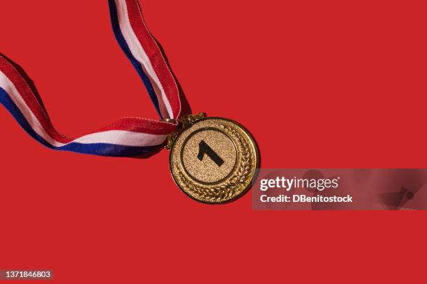 gold medal of sporting achievements for the first classified, on a red background. concept of winner, medals, honor and sports competition. - erster platz stock-fotos und bilder