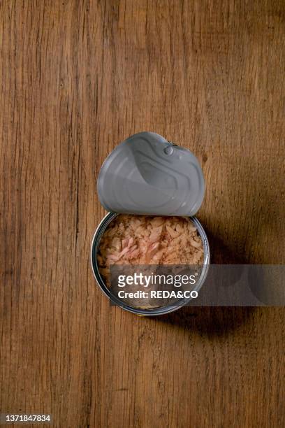 Canned tuna fish in oil in opened can over wooden background, Top view, copy space.