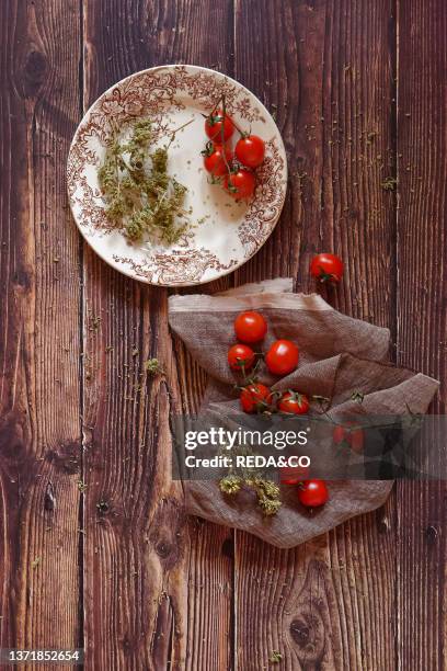 Traditional ingredients of Italian cuisine. Fresh cherry tomato. Origan on a wooden background. Italy. Europe.