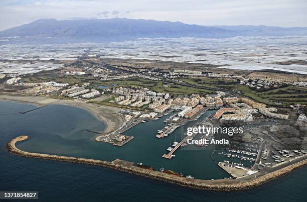 Aerial view of the marina of Almerimar and 'Sea of Plastic' with its fruit and vegetable growing under greenhouses and plastic tarpaulins, as far as...