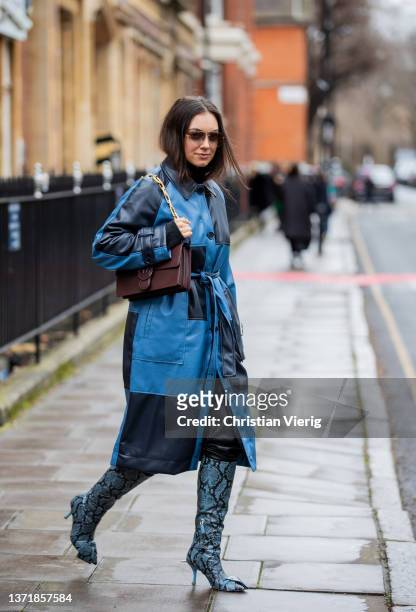 Guest is seen wearing checkered navy blue coat, brown bag, boots with snake print outside 16Arlington during London Fashion Week February 2022 on...