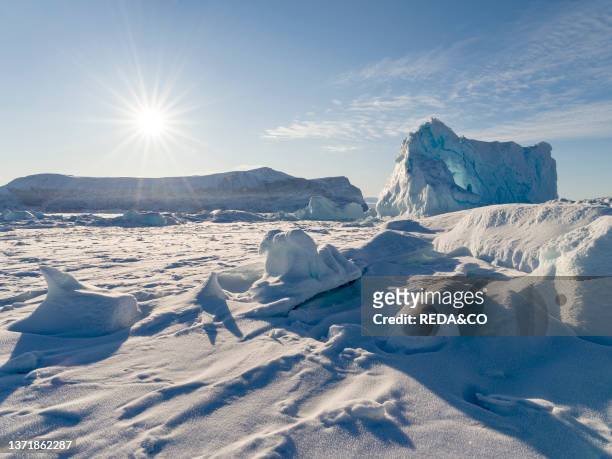 Icebergs frozen into the sea ice of the Uummannaq fjord system during winter in the the north west of Greenland. Far beyond the polar circle. North...