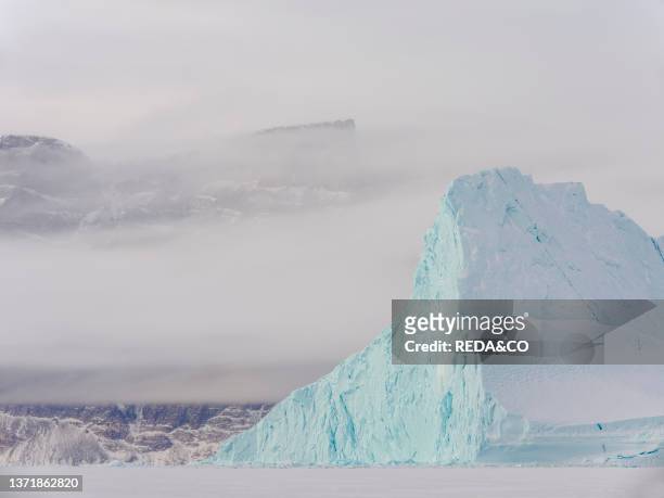 Icebergs in front of Stoeren Island. Frozen into the sea ice of the Uummannaq fjord system during winter in the the north west of Greenland. Far...