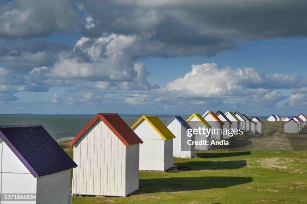 Gouville sur Mer : beach huts with colourful roofs and cloudy sky over the dunes along the coast of Cotentin.