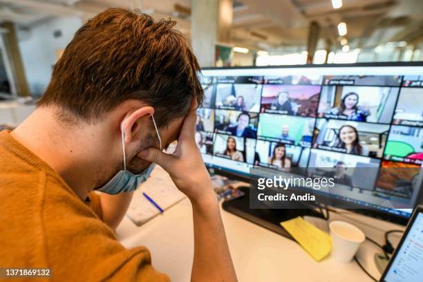 Coronavirus outbreak, Covid 19, remote working, video conference in a company. Man sitting at his desk holding his head with his hands.
