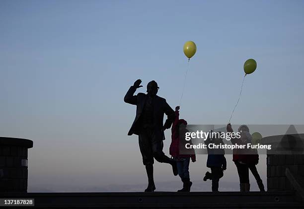 Children with balloons play beside the statue of British comedy legend Eric Morecambe on January 16, 2012 in Morecambe, England. According to...