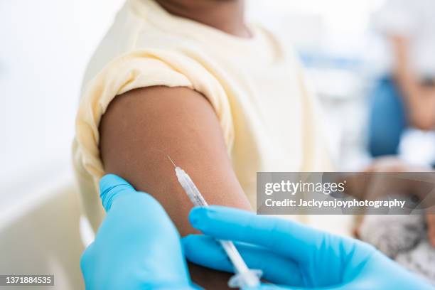 immunisation. protecting children from diseases. close-up nurse in medical gloves giving injection to little patient. brave boy getting a flu shot at doctor's office and looking at needle - pharmacist and patient imagens e fotografias de stock