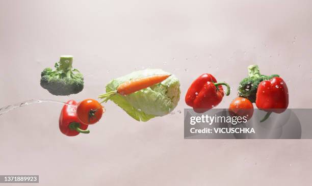 flying vegetables with water splash at pale beige background - zero gravity food stock pictures, royalty-free photos & images