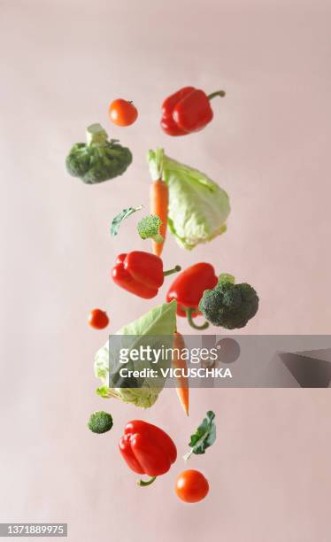various colorful vegetables falling at pale beige background - flight food stock pictures, royalty-free photos & images