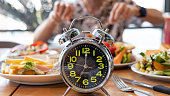 Selective focus of  Alarm clock with  young man eating a healthy food as Intermittent fasting, time-restricted eating-Diet breakfast image