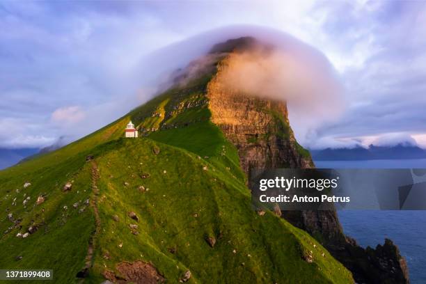 kallur lighthouse on green hills of kalsoy island at sunset. faroe islands, denmark. - faroe islands stockfoto's en -beelden