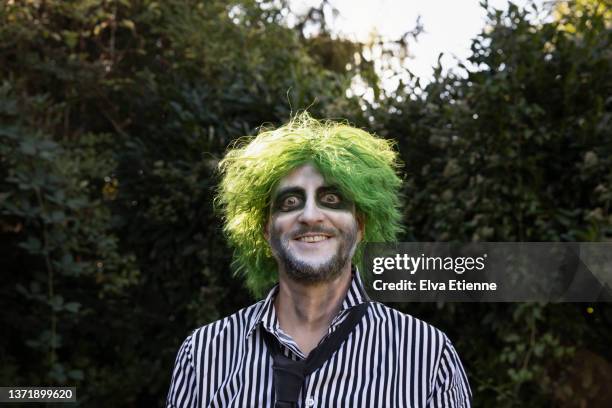 mature adult wearing a shirt and tie, with green wavy hair, halloween face paints and carefree facial expression - funny facial hair stock pictures, royalty-free photos & images