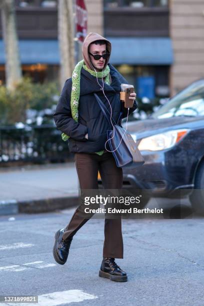Guest wears a brown hoodie sweater, a green and white print pattern braided wool scarf, a black puffer jacket, a black shiny leather shoulder bag...