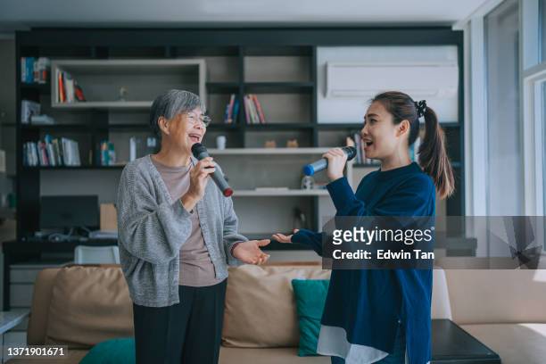 asiatisch-chinesische senior-frau, die karaoke tanzt mit ihrer tochter im wohnzimmer während der wochenend-freizeitaktivitäten - karaoke anlage stock-fotos und bilder
