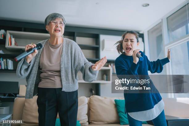 asian chinese senior woman singing karaoke dancing with her daughter in living room during weekend leisure activities - chinese dance imagens e fotografias de stock