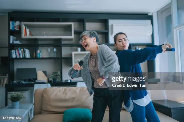 asian chinese senior woman singing karaoke dancing with her daughter in living room during weekend leisure activities - asian 個照片及圖片檔