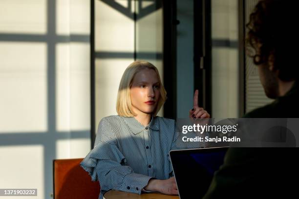 junge attraktive blonde startup-mitarbeiterin mit erhobenem zeigefinger - co owner stock-fotos und bilder