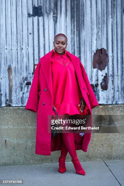 Guest wears gold large pendant earrings, a red shirt, a red matching V-neck dress, a red oversized fluffy log coat, red tights, a gold Valentino...