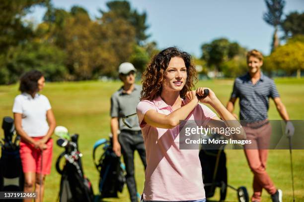 smiling golfer teeing off in golf field - natural shot female stock-fotos und bilder