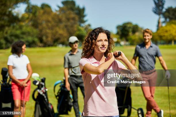 smiling golfer teeing off in golf field - women's golf stockfoto's en -beelden