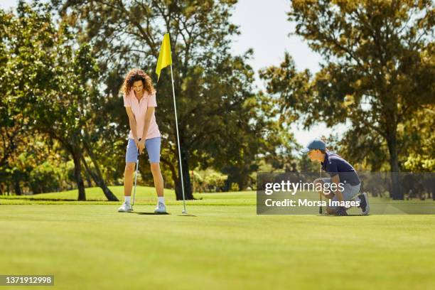 female golfer taking shot on golf field - putting clothes son stock pictures, royalty-free photos & images
