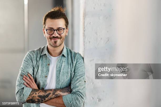 hombre hipster confiado de pie junto a la pared. - diseñador gráfico fotografías e imágenes de stock